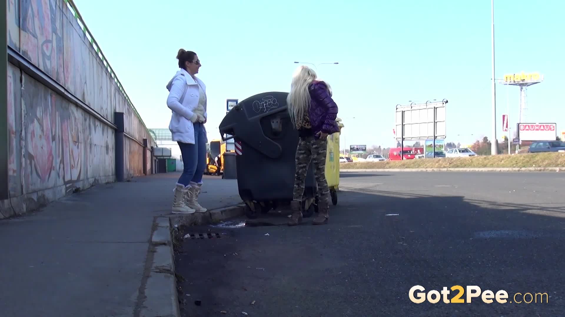 Two girlfriends piss in public next to bus stop